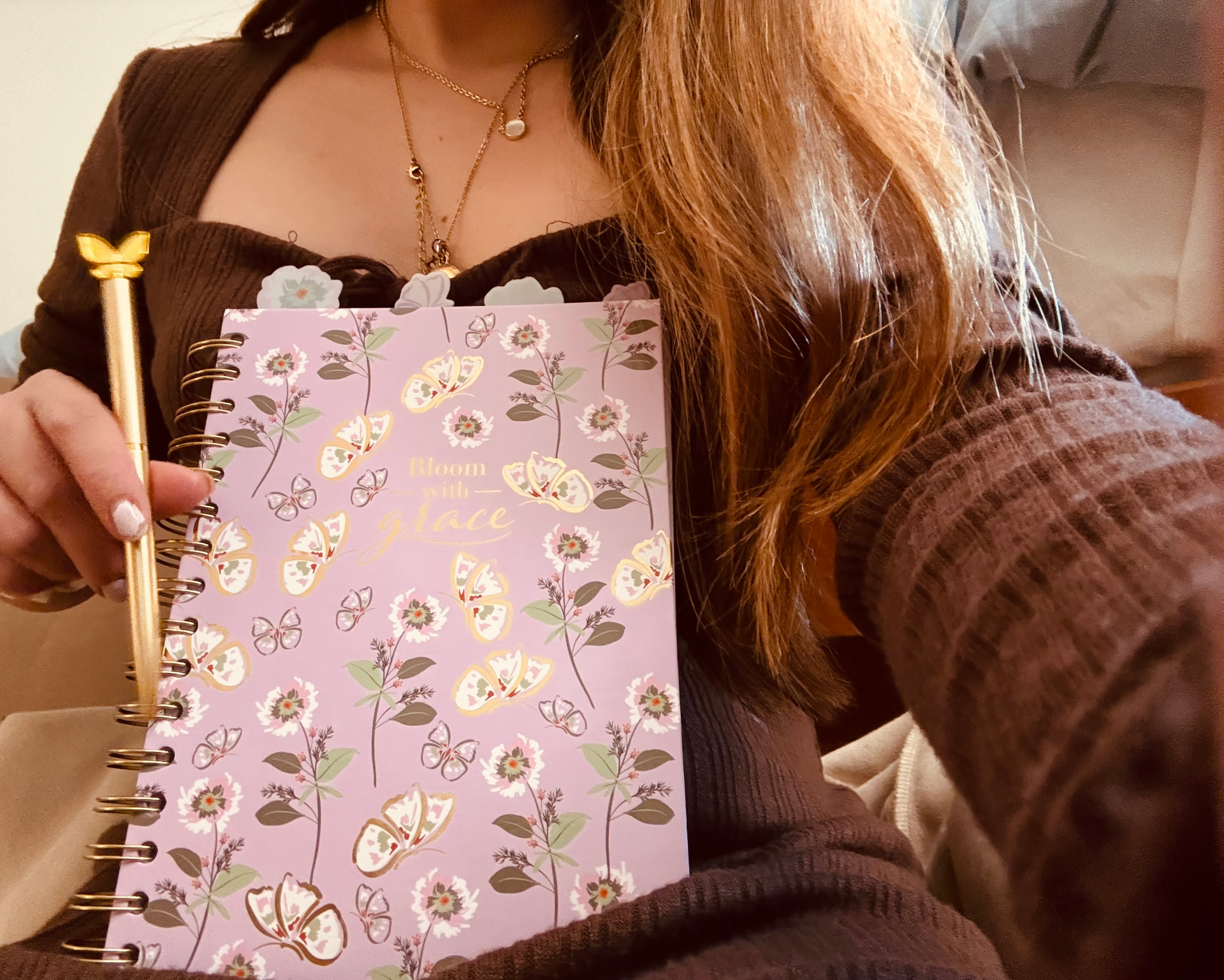 Bloom with Grace journal and golden butterfly pen, held in someone's arms